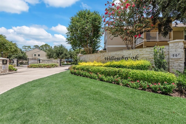 community / neighborhood sign featuring a lawn and fence