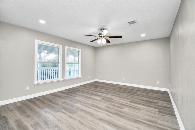 unfurnished room featuring wood finished floors, visible vents, and baseboards