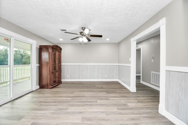 empty room with a wainscoted wall, visible vents, and light wood-style floors