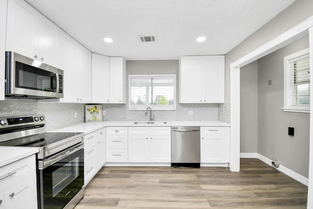 kitchen featuring stainless steel appliances, plenty of natural light, light countertops, and a sink