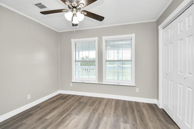 unfurnished bedroom featuring dark wood-type flooring, ornamental molding, a closet, and baseboards