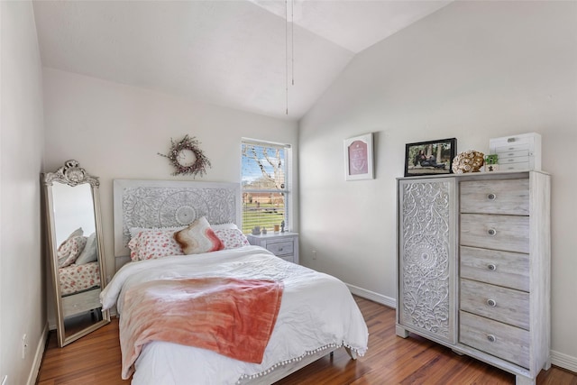 bedroom with vaulted ceiling, wood finished floors, and baseboards