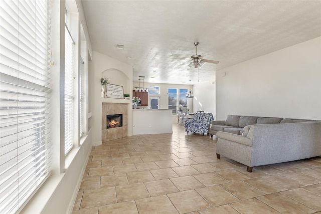 living room with visible vents, ceiling fan, a tiled fireplace, and light tile patterned floors