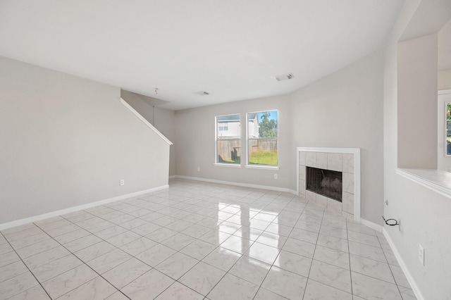 unfurnished living room featuring a tile fireplace, visible vents, and baseboards