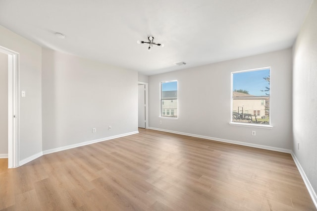 unfurnished room featuring baseboards, light wood finished floors, visible vents, and a healthy amount of sunlight