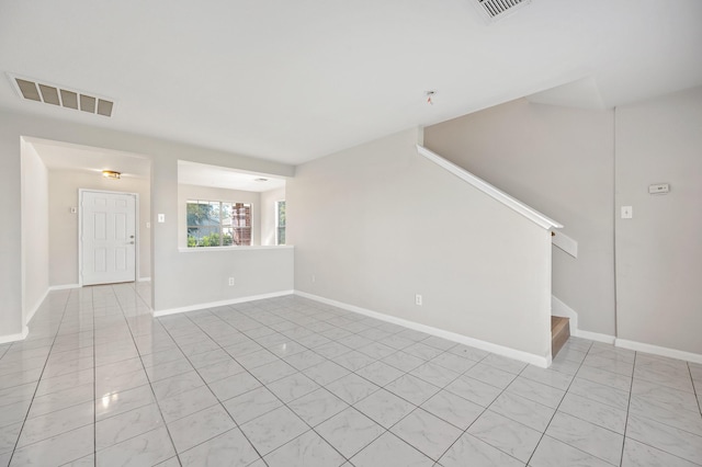 empty room featuring visible vents, stairway, and baseboards