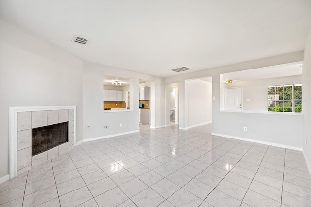 unfurnished living room featuring baseboards, visible vents, and a tiled fireplace