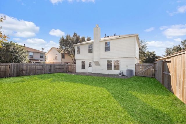 rear view of house with a lawn, a chimney, cooling unit, and a fenced backyard