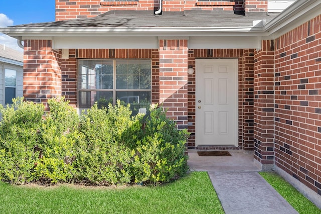 property entrance featuring brick siding and a shingled roof