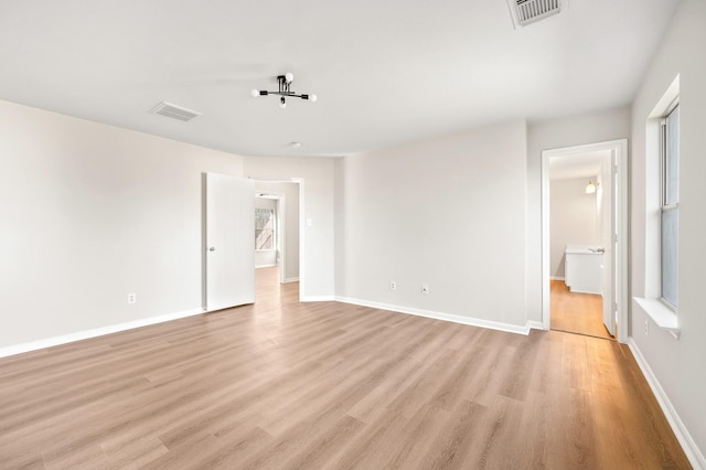 spare room featuring light wood-style floors, visible vents, and baseboards