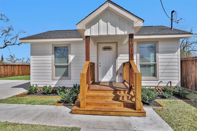 view of front of house featuring board and batten siding, fence, and a shingled roof