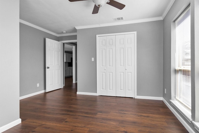 unfurnished bedroom featuring baseboards, visible vents, dark wood finished floors, and crown molding