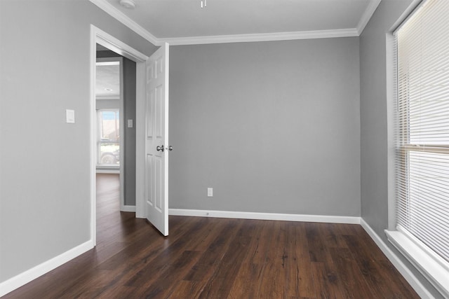 unfurnished room with crown molding, dark wood finished floors, and baseboards