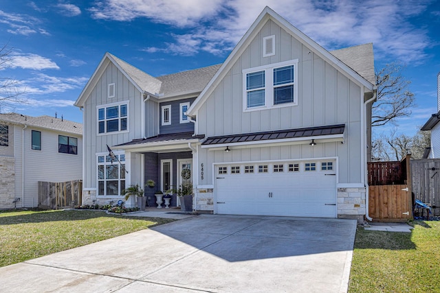 view of front facade with an attached garage, fence, driveway, a front lawn, and board and batten siding