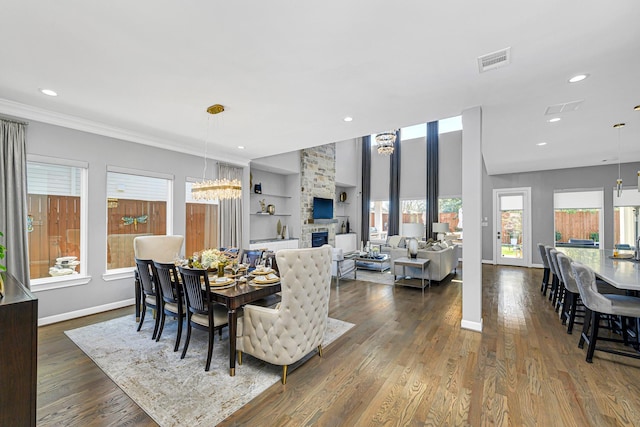 dining space featuring built in features, baseboards, visible vents, dark wood-type flooring, and a fireplace