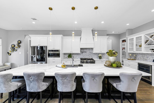 kitchen featuring beverage cooler, white cabinets, custom exhaust hood, range, and stainless steel fridge