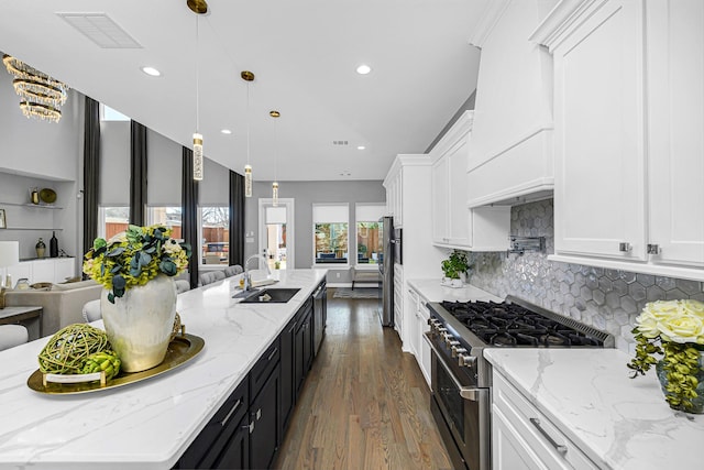 kitchen with a sink, visible vents, white cabinets, open floor plan, and appliances with stainless steel finishes