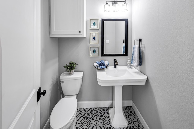 bathroom with tile patterned flooring, baseboards, and toilet