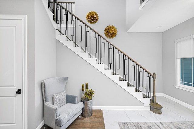 stairway with marble finish floor and baseboards