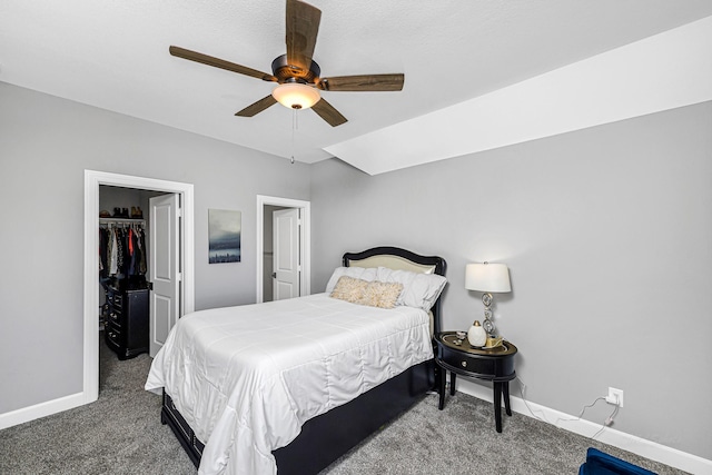 carpeted bedroom with ceiling fan, baseboards, a walk in closet, and a closet