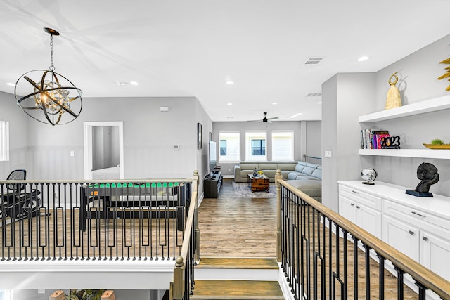 interior space featuring recessed lighting, visible vents, white cabinetry, wood finished floors, and ceiling fan with notable chandelier