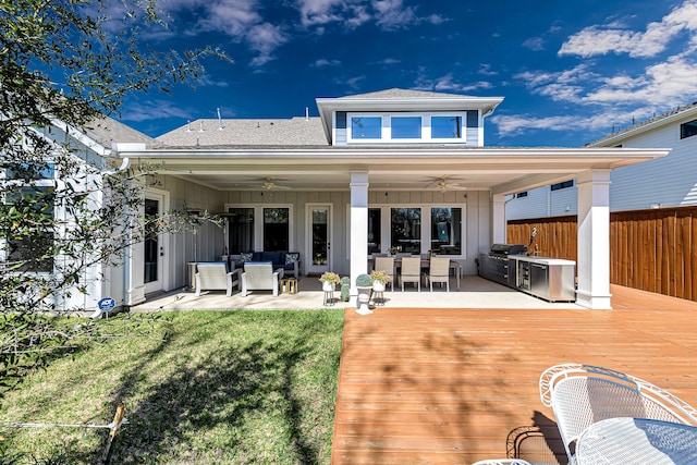 rear view of house with fence, exterior kitchen, a wooden deck, an outdoor living space, and board and batten siding