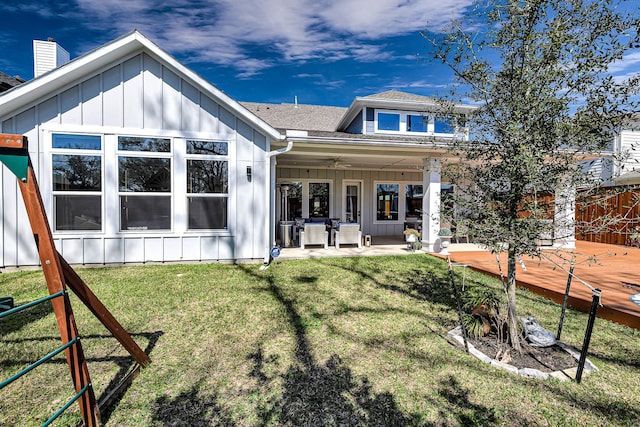 rear view of property featuring roof with shingles, board and batten siding, and a yard