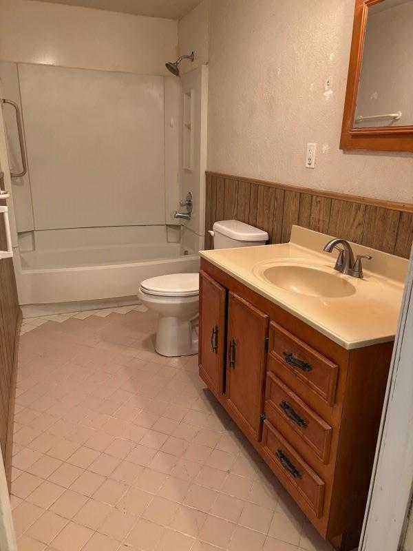 bathroom with wainscoting, toilet, tub / shower combination, vanity, and wood walls