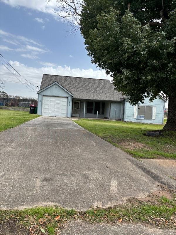 view of front of property with an attached garage, driveway, roof with shingles, and a front yard