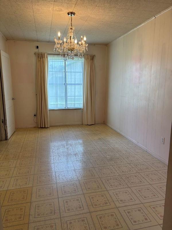 unfurnished room featuring a notable chandelier, a textured ceiling, and light floors