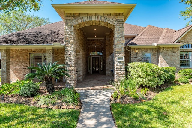 property entrance with stone siding, brick siding, and roof with shingles