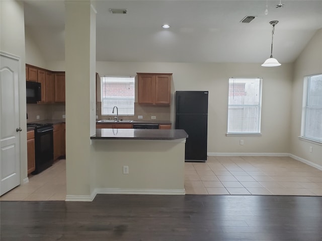 kitchen with a sink, black appliances, lofted ceiling, and a wealth of natural light