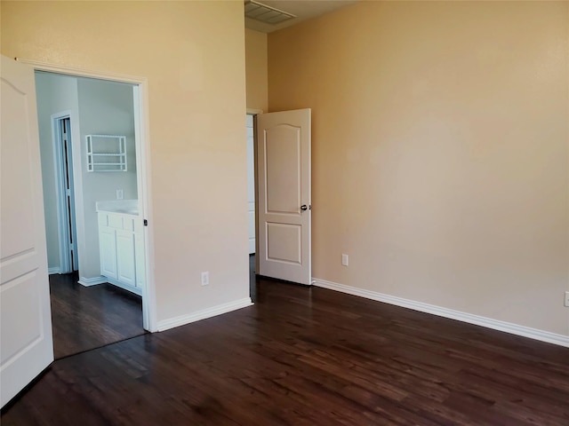 unfurnished bedroom featuring dark wood-type flooring, visible vents, and baseboards