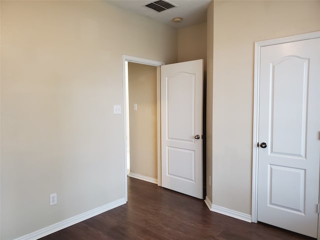 unfurnished bedroom featuring dark wood-style flooring, visible vents, and baseboards