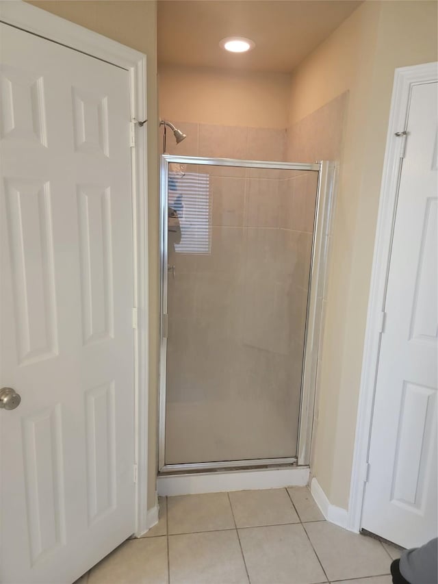 bathroom with baseboards, a shower stall, and tile patterned floors