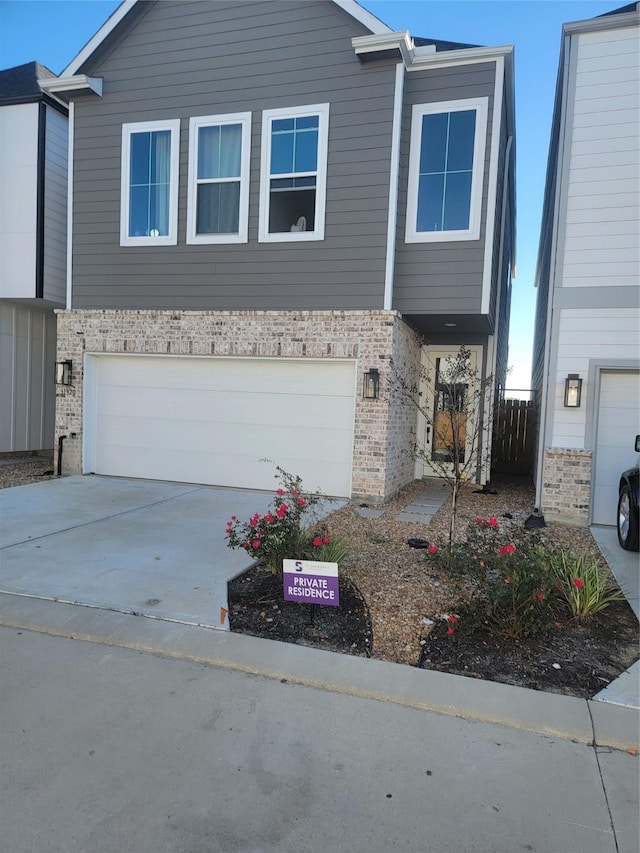 view of front of home with concrete driveway, brick siding, and an attached garage