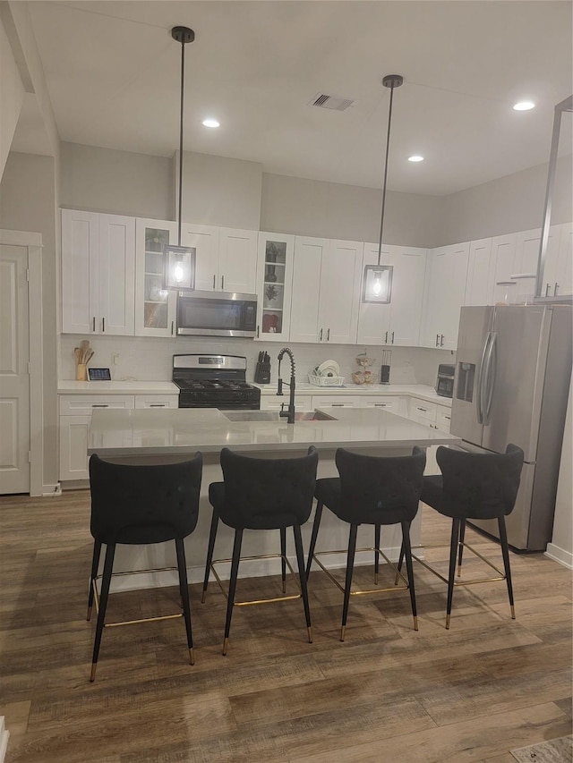 kitchen with dark wood finished floors, a breakfast bar area, stainless steel appliances, light countertops, and a sink