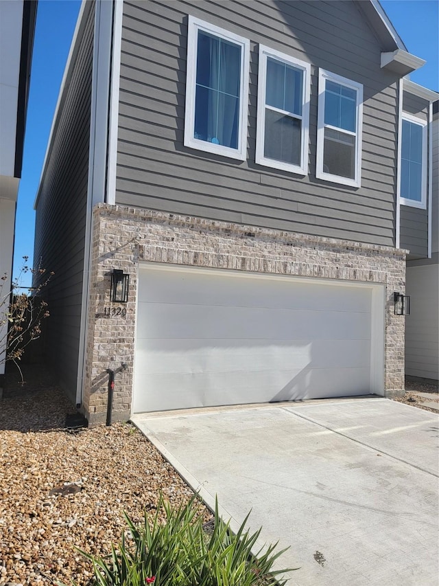 view of home's exterior featuring an attached garage, concrete driveway, and brick siding