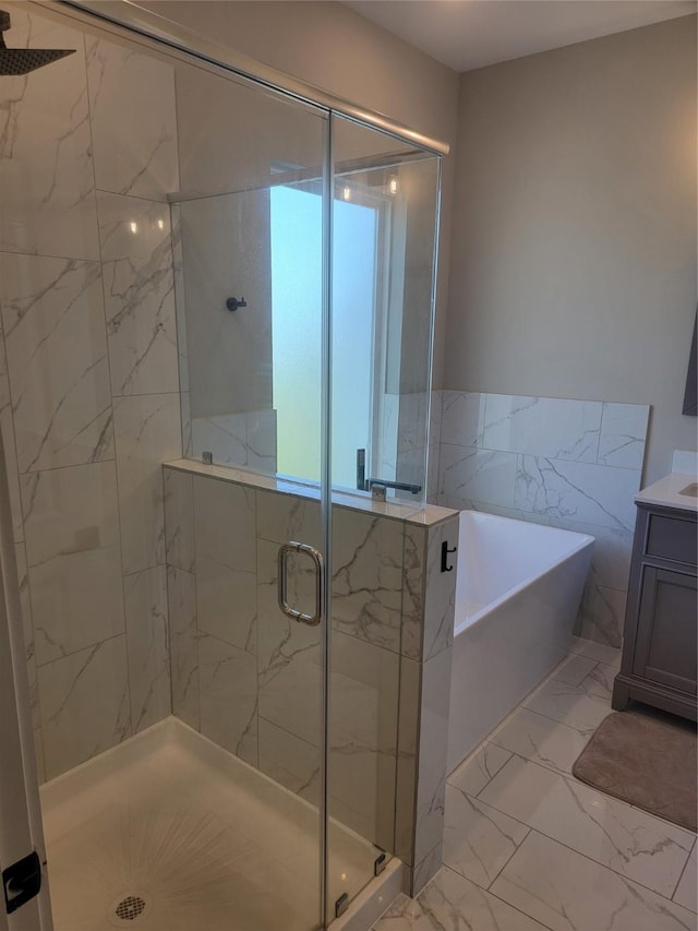 full bath featuring marble finish floor, a shower stall, a freestanding bath, and vanity