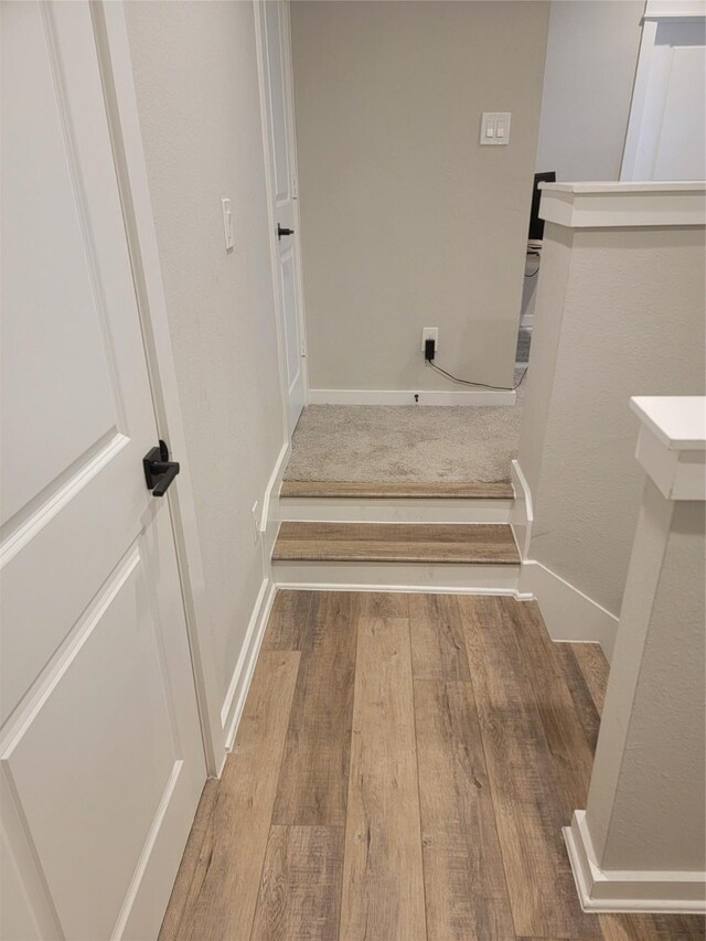 staircase featuring baseboards and wood finished floors