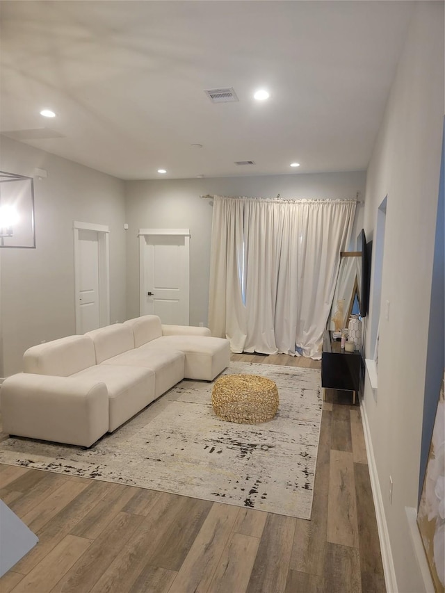 living room featuring visible vents, baseboards, wood finished floors, and recessed lighting