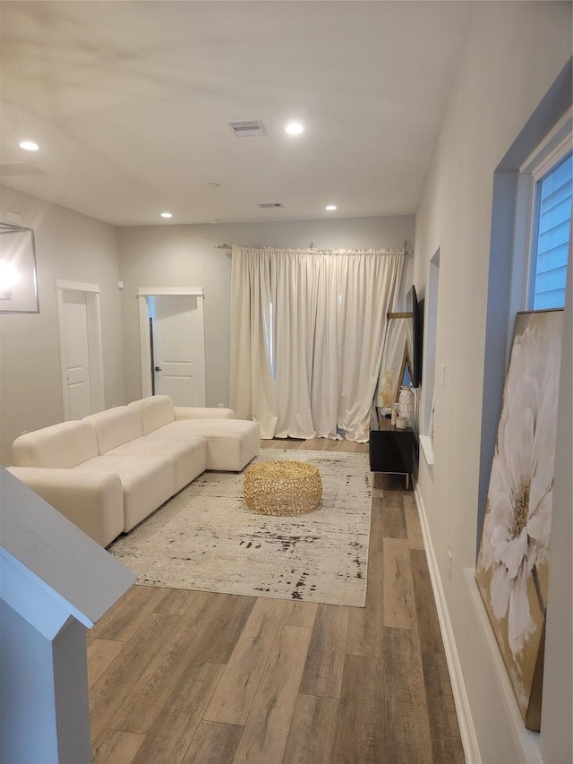 living area with baseboards, visible vents, wood finished floors, and recessed lighting