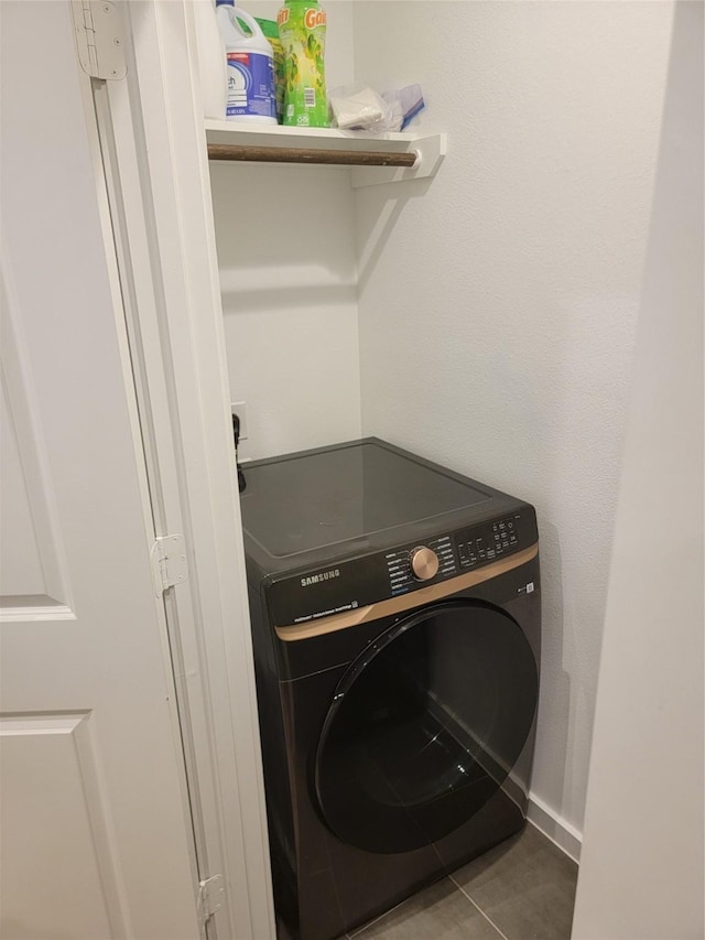 clothes washing area featuring laundry area, washer / clothes dryer, tile patterned flooring, and baseboards