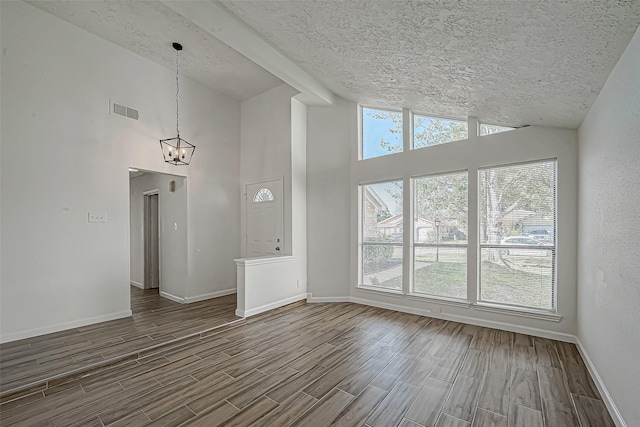 spare room with wood finish floors, visible vents, lofted ceiling with beams, and baseboards