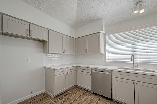 kitchen featuring dishwasher, gray cabinets, a sink, and wood tiled floor