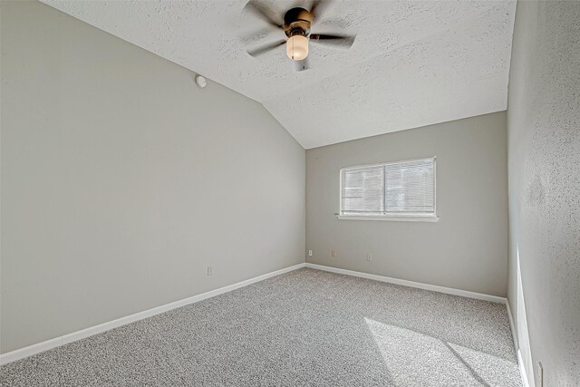 carpeted spare room with lofted ceiling, a ceiling fan, baseboards, and a textured ceiling