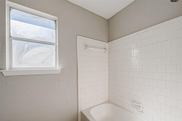 bathroom with shower / bath combination and a textured wall