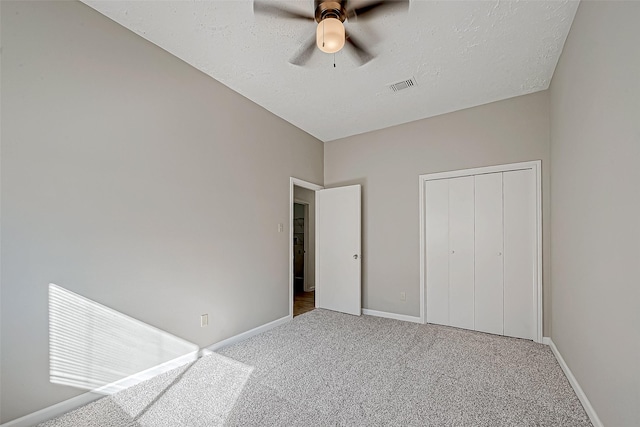 unfurnished bedroom featuring baseboards, a textured ceiling, visible vents, and carpet flooring