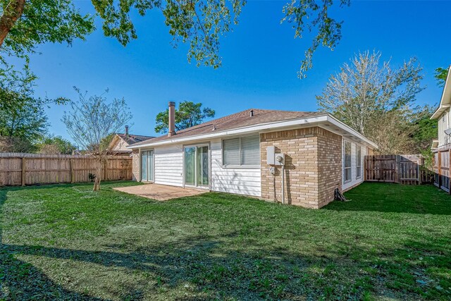 back of property with a fenced backyard, a patio, a lawn, and brick siding