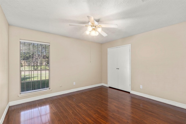 spare room with a textured ceiling, wood-type flooring, a ceiling fan, and baseboards